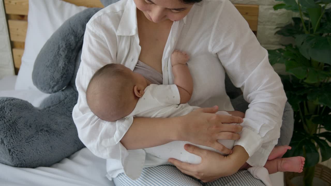 A new mother breastfeeding her new baby In cradle hold position